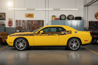 Yellow Dodge Challenger with SCATPACK side-stripe graphics in a bright classic muscle-car garage